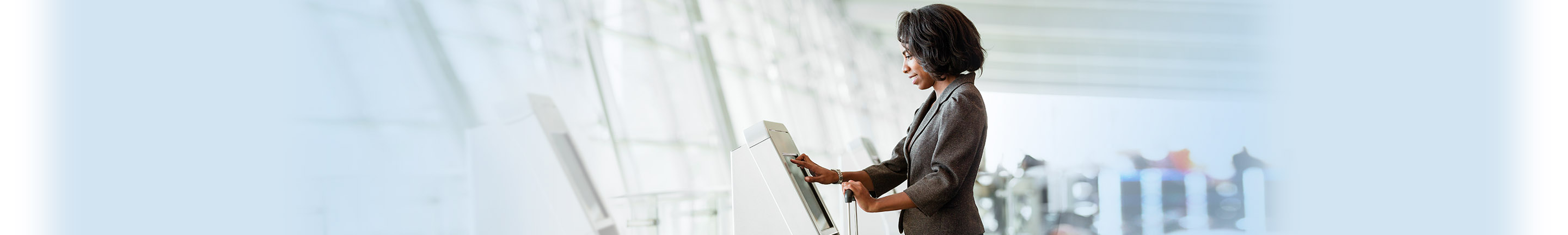 Sighted woman standing at touch screen kiosk.